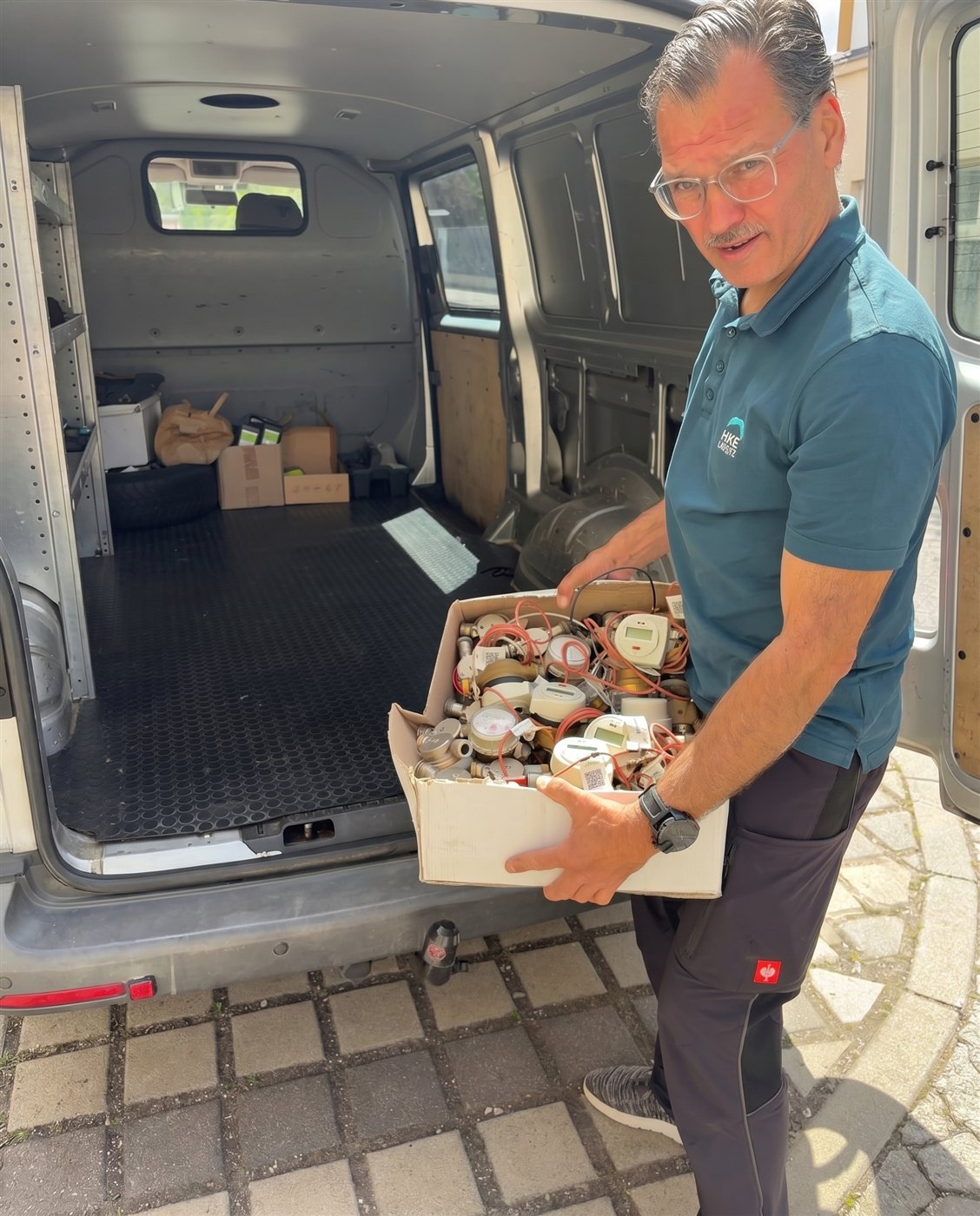 HKE-Mitarbeiter lädt eine Kiste mit Messgeräten in den Firmenwagen.